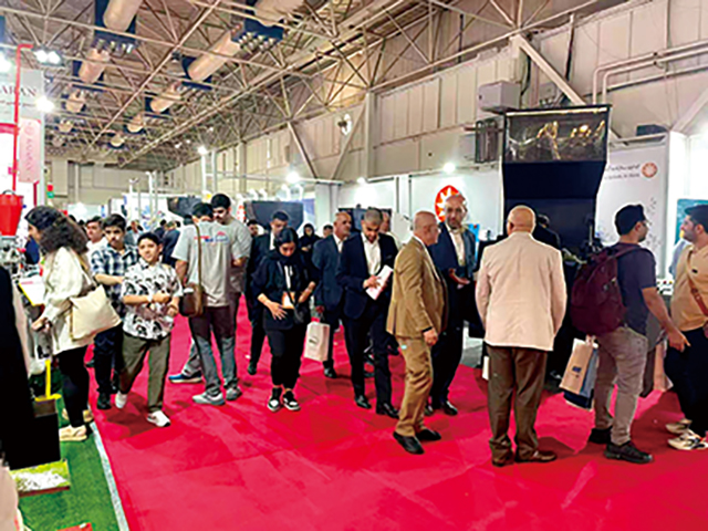 5.展館主通道人流密集，多位西裝革履的采購商正在觀看產品演示